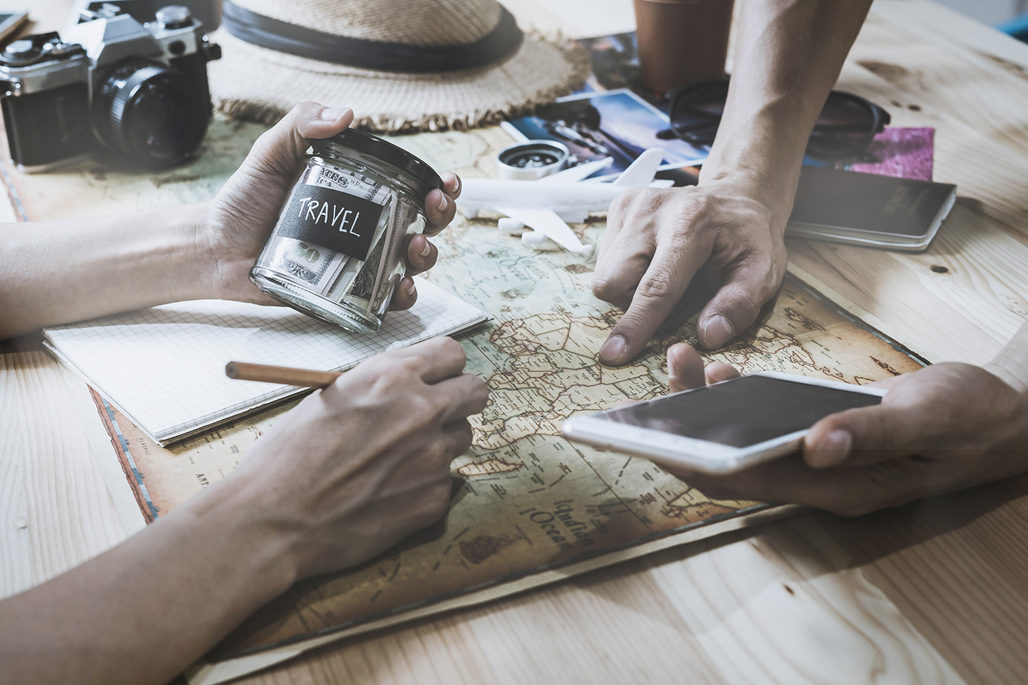 Traveller planning an itinerary using maps, travel notes and camera gear