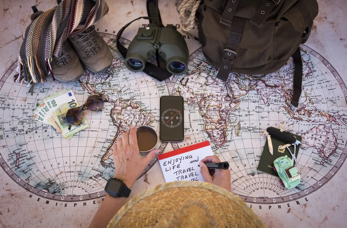 A backpacker overlooking a world map and journalling plans for a year-long RTW trip